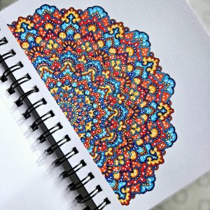 Red, blue and orange mandala art created by Noor Khan with gel pens on mixed media paper