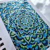 Blue and green mandala art created by Noor Khan with pearlescent watercolors on mixed media paper