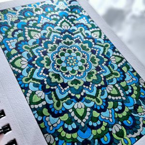 Blue and green mandala art created by Noor Khan with pearlescent watercolors on mixed media paper