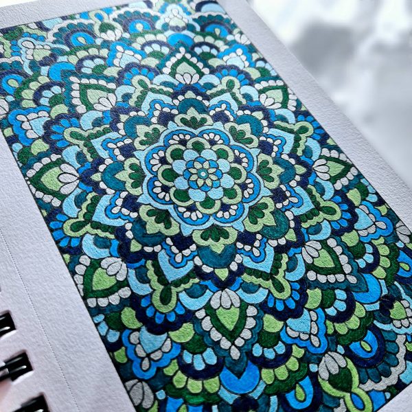 Blue and green mandala art created by Noor Khan with pearlescent watercolors on mixed media paper
