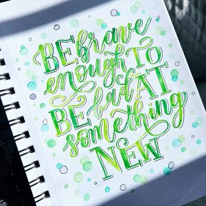 Hand‑lettered quote reading “Be brave enough to be bad at something new” painted in green with bubbles around it